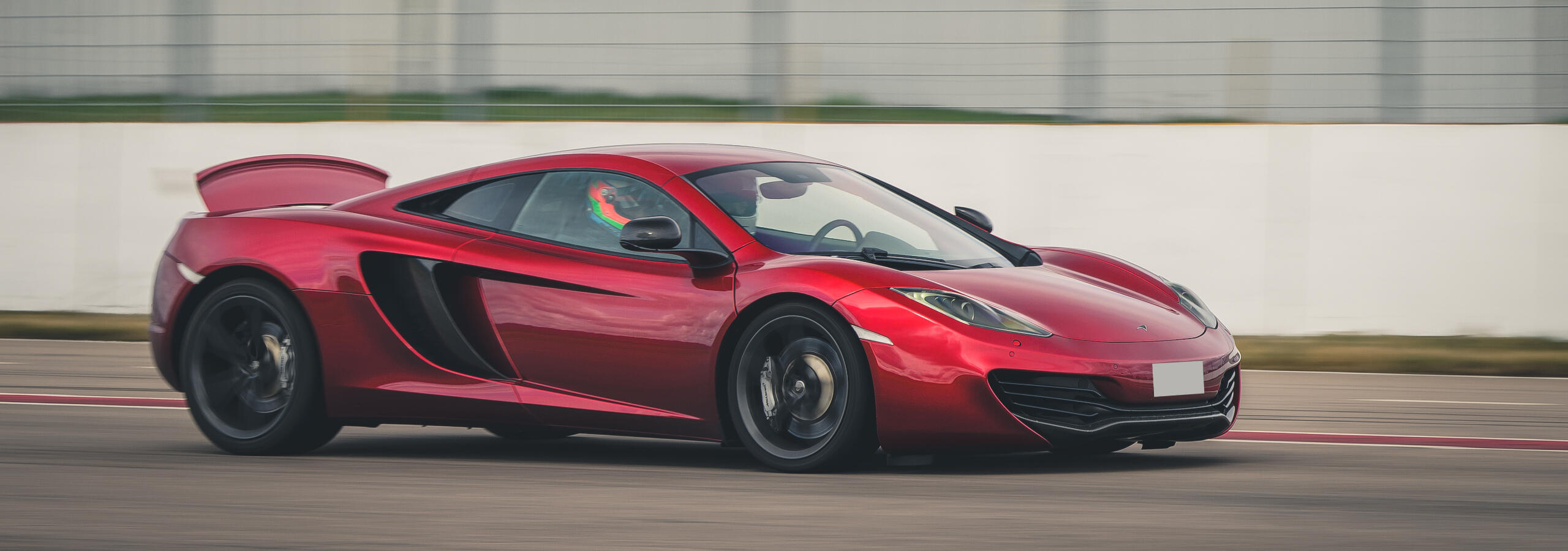 Röd McLaren på bana – med en passion för supersportbilar.