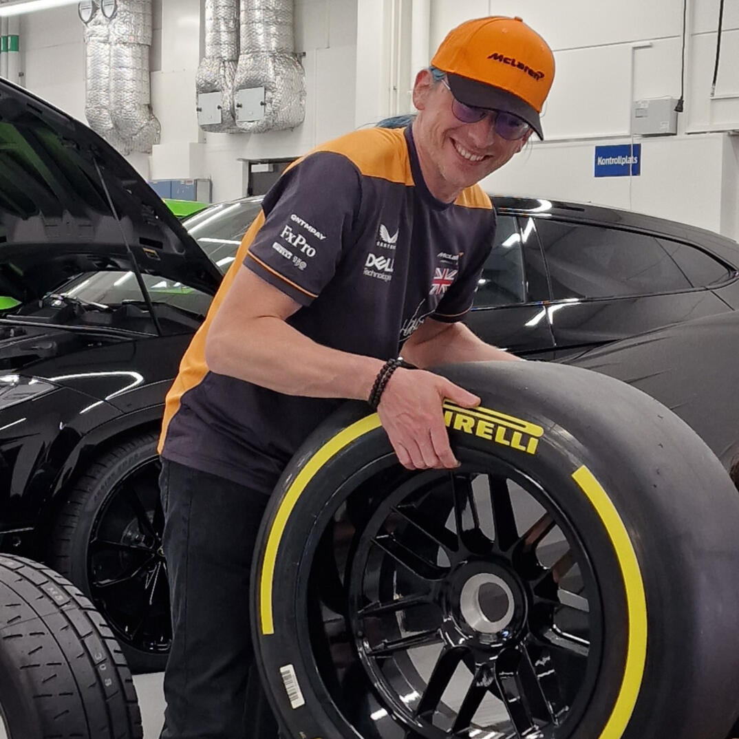 Tekniker i depåmiljö med Pirelli-slick framför sportbil.